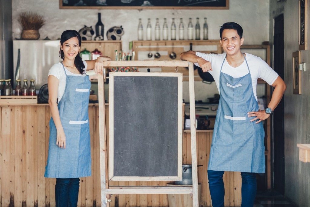 Restaurant owners standing with blank chalkboard