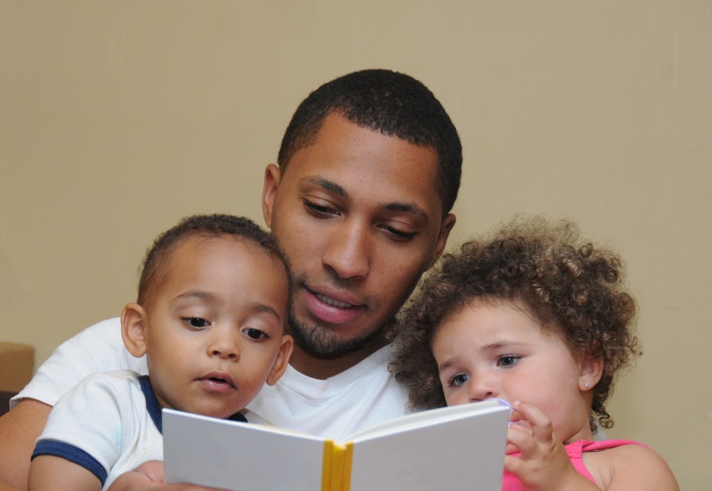 man reading a book to his kids